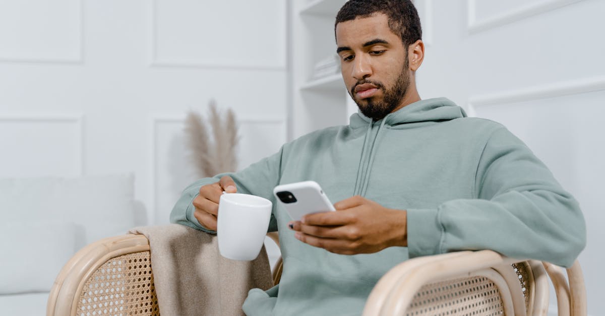 Man in Gray Hoodie Holding White Ceramic Mug